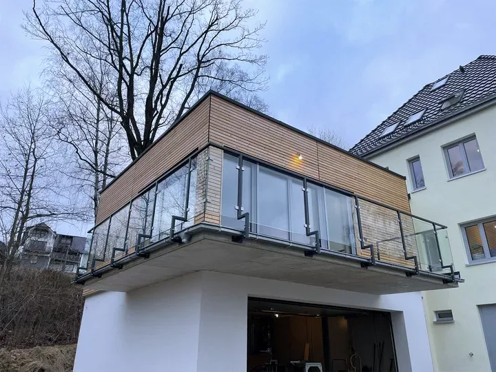 Auskragender Balkon mit Glasgeländer an einem modernen Anbau in der Dämmerung