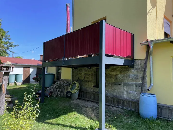 Anbaubalkon mit roter Kunststofffüllung auf Stahlkonstruktion in Anthrazit