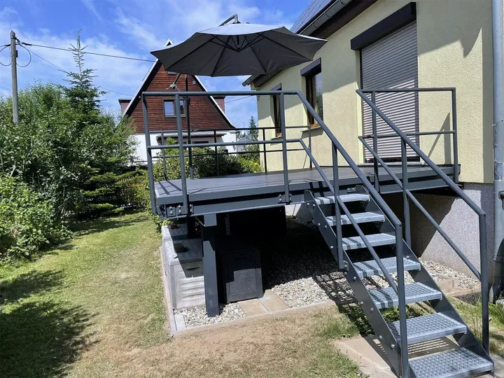 Anthrazitfarbene Treppe mit Gitterroststufen zur Terrasse im Garten