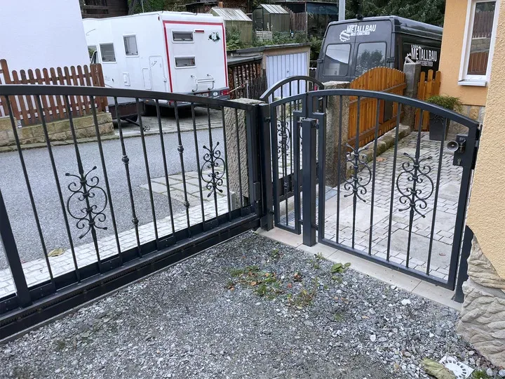 Anthrazitfarbenes Schiebetor mit Zierelementen an einer Einfahrt
