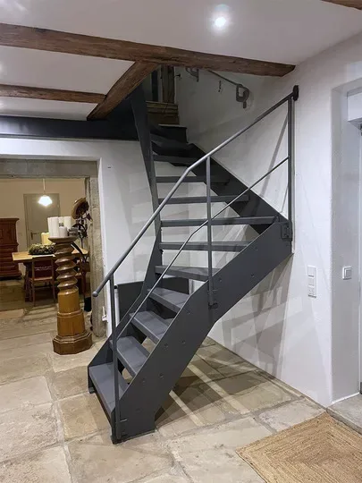 Halbgewendelte Stahltreppe im Wohnraum, grau lackiert