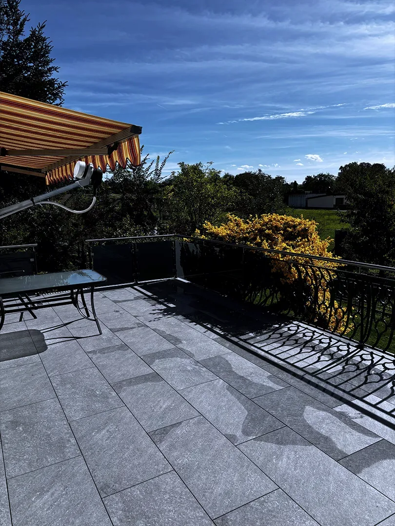 Ecke des Terrassengeländers aus grauem Mattglas unter der Markise
