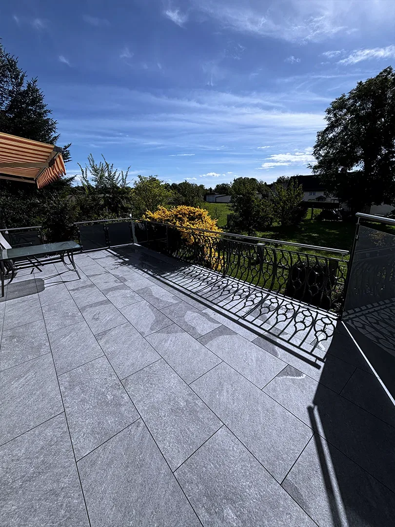 Aufgearbeitete Geländerfelder mit Zierbögen an der Terrasse, Blick in den Garten