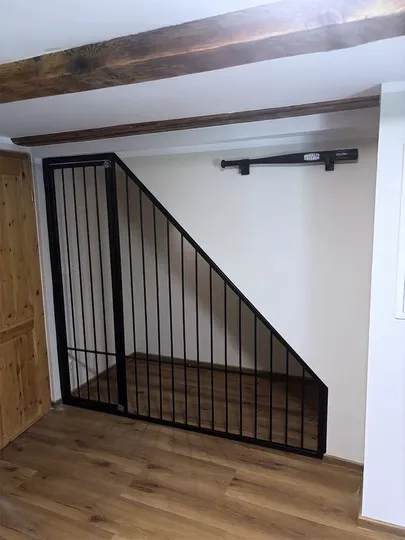 Schwarze Abtrennung aus Stahlstäben unter einer Wohnraumtreppe