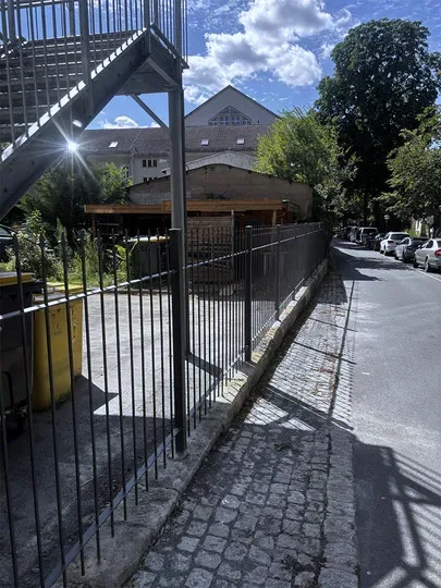 Anthrazitfarbener Stabzaun mit Spitzen entlang des Gehwegs