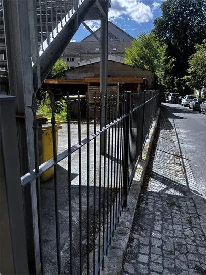 Zaun mit senkrechten Stäben entlang einer Straße